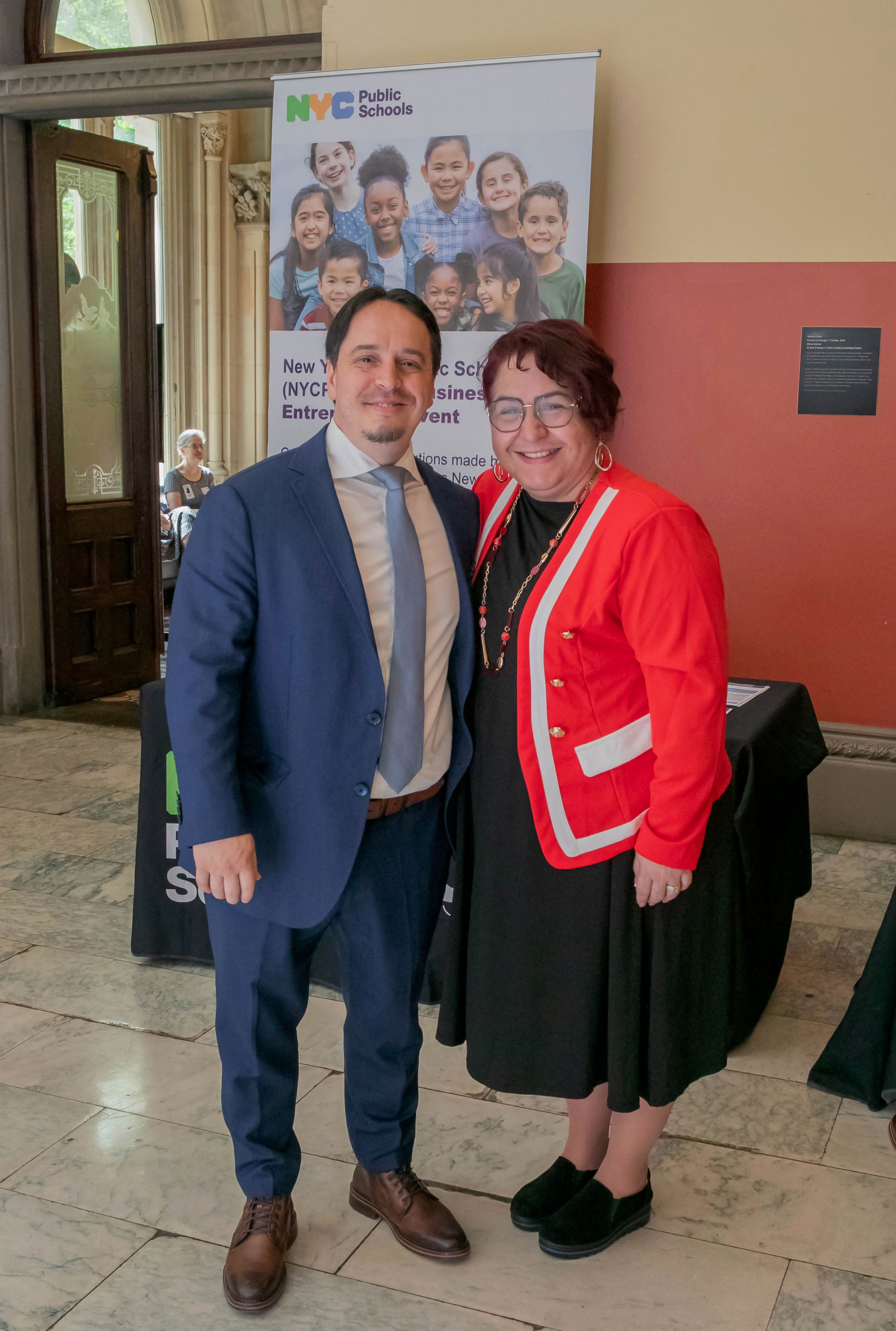 Man in blue suit standing next to woman in red jacket