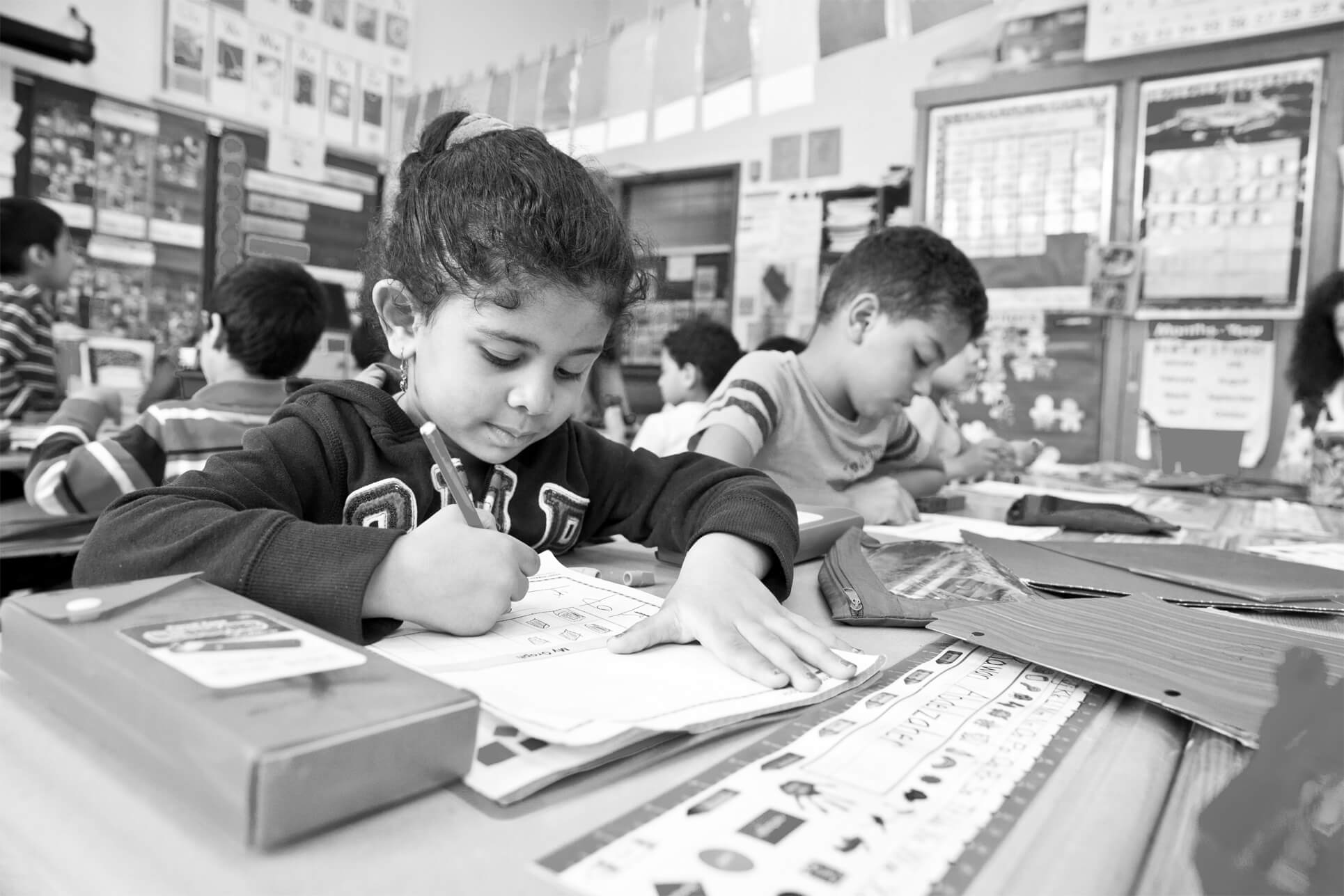 Special Education Preschool Resources Children writing in workbooks in a classroom.